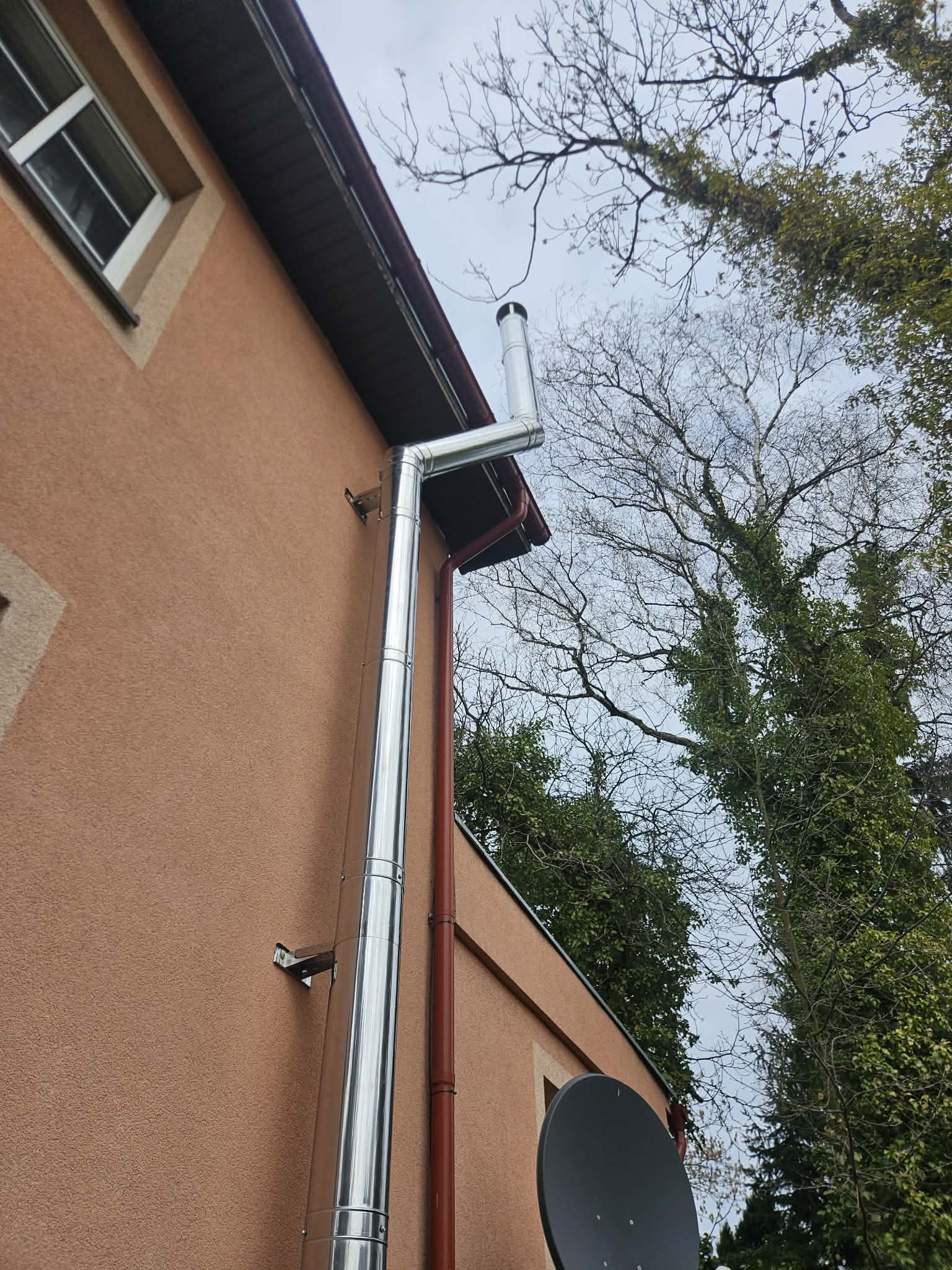 Zewnętrzny komin stalowy z obejściem okapu na elewacji domu