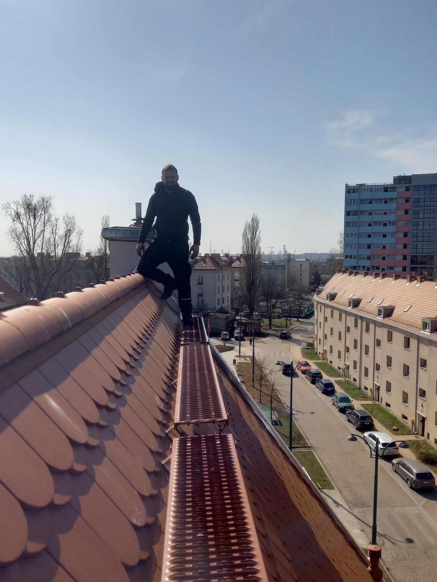 Ława kominiarska na dachu pokrytym czerwoną dachówką karpiówką